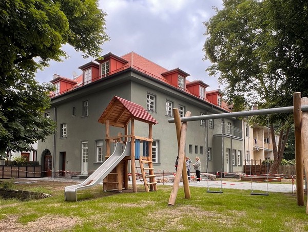 Außenansicht des Hauses mit Spielplatz im Vordergrund